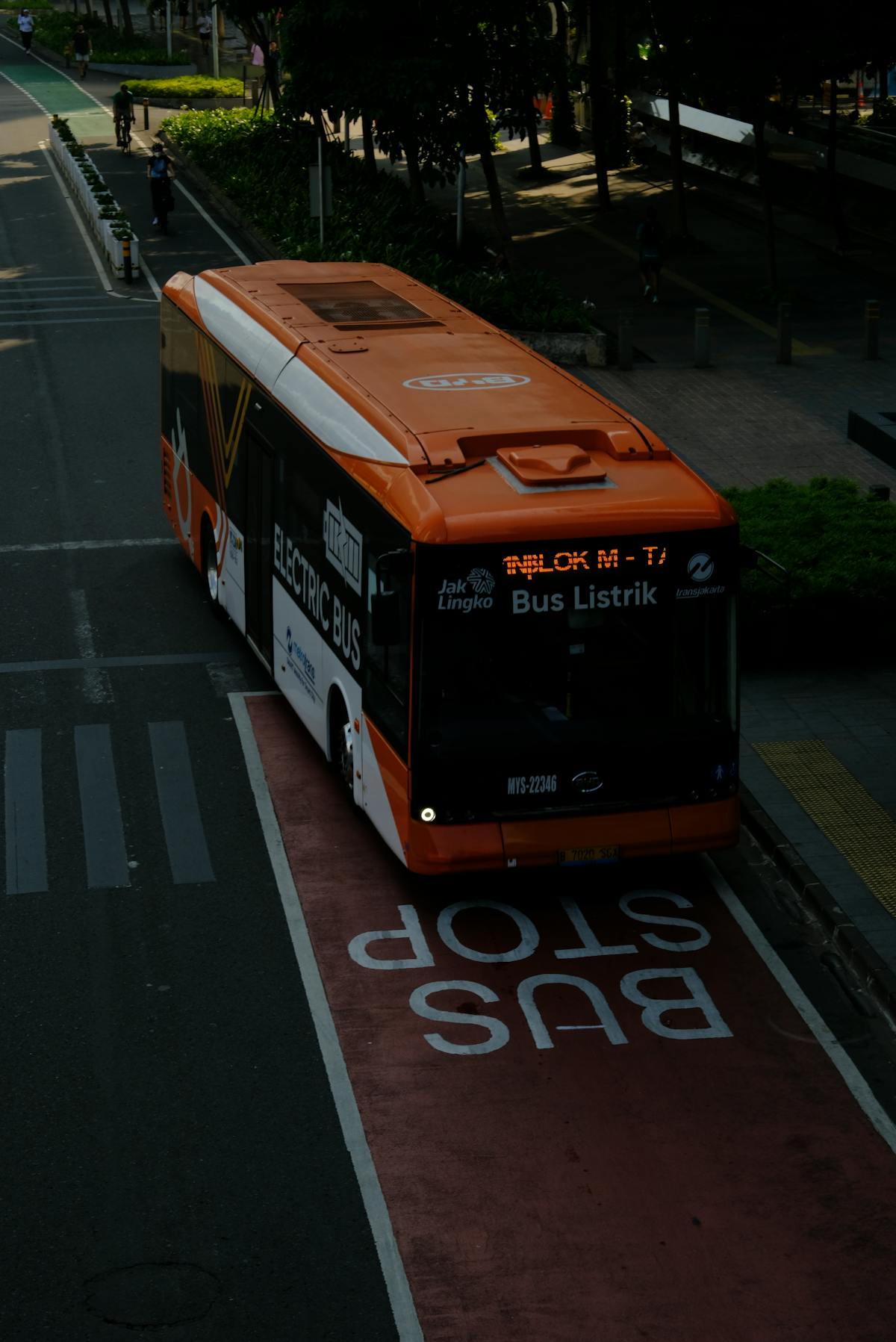 Orange electric bus driving in a dedicated bus lane in the city